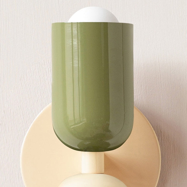 Decorative wall sconce with green glass shade and beige base on a neutral background