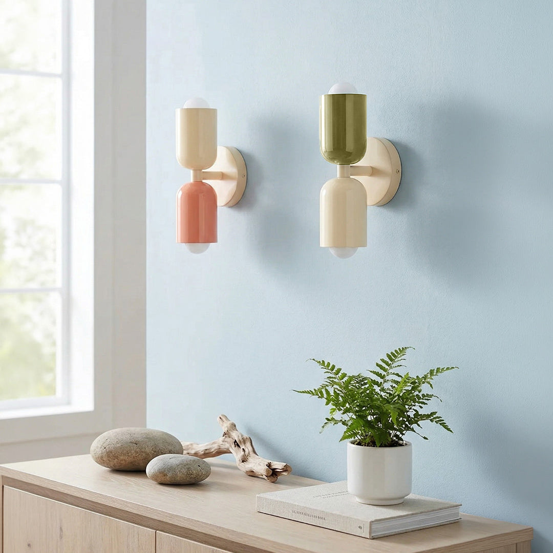 Two wall sconces on a light blue wall with a wooden console table and plant.