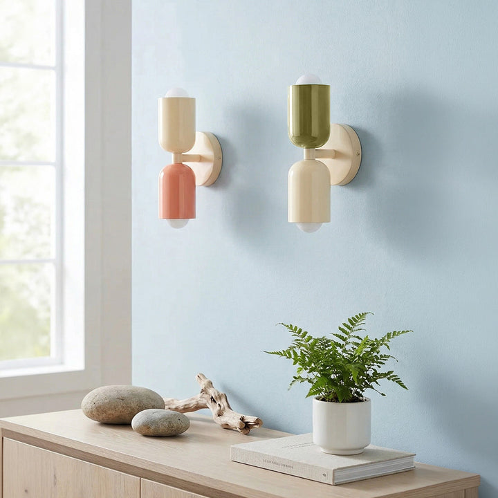 Two wall sconces on a light blue wall with a wooden console table and plant.