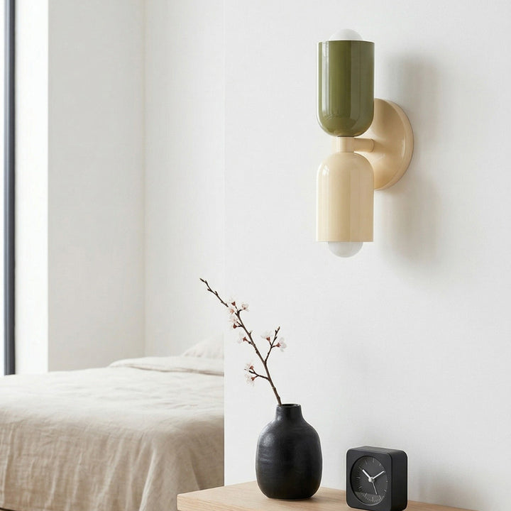 Modern wall sconce with green and pink design on a neutral wall.