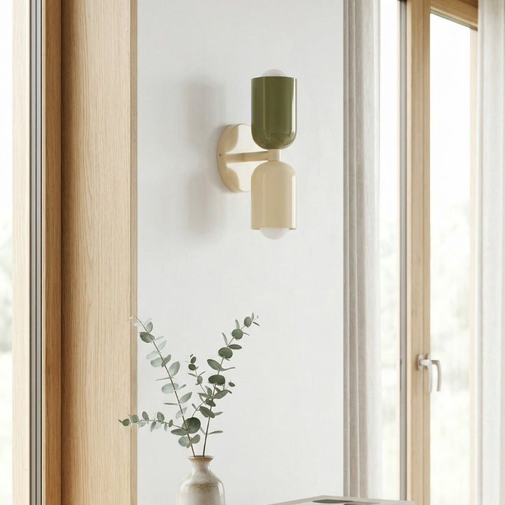 Modern wall sconce on a white wall with a vase and books on a wooden surface.
