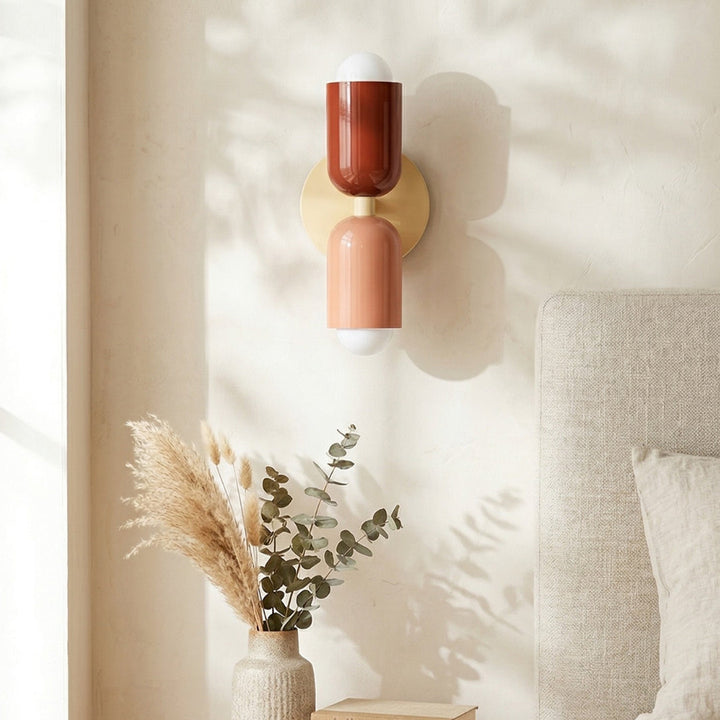 Decorative wall sconce with two colored shades in a room setting.