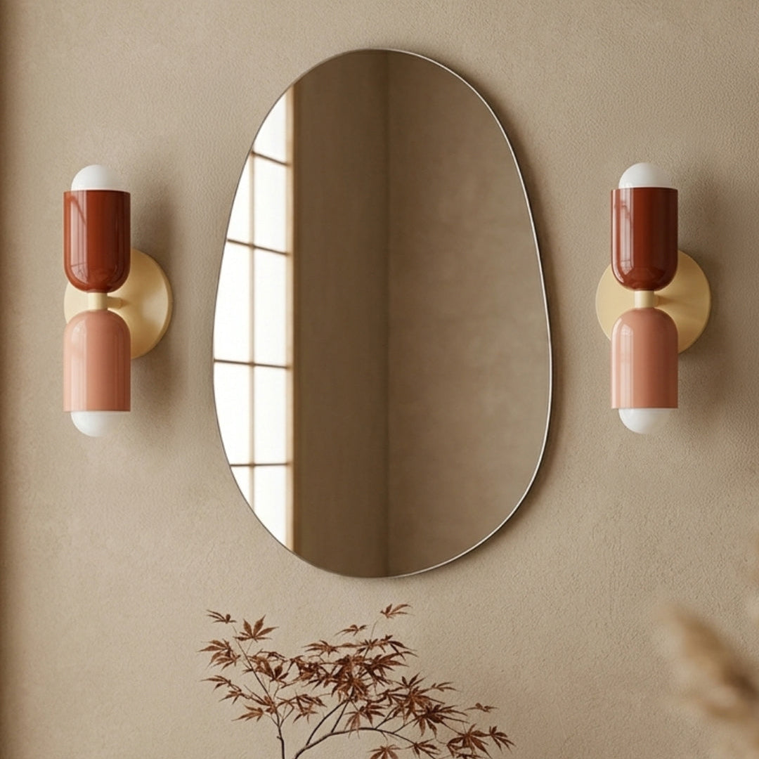 Modern wall sconce with pink and red design on a mustard yellow wall.
