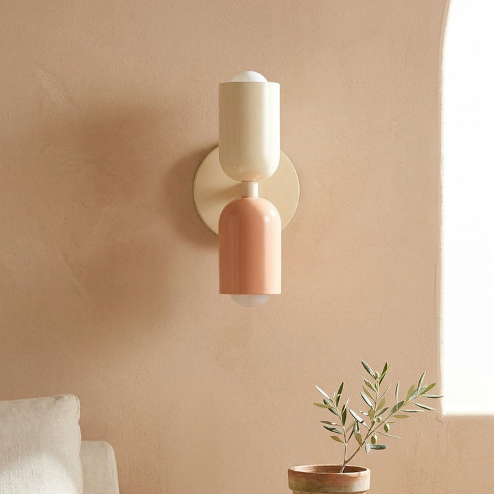 Wall-mounted light fixture on a beige wall with a plant and chair in the foreground.