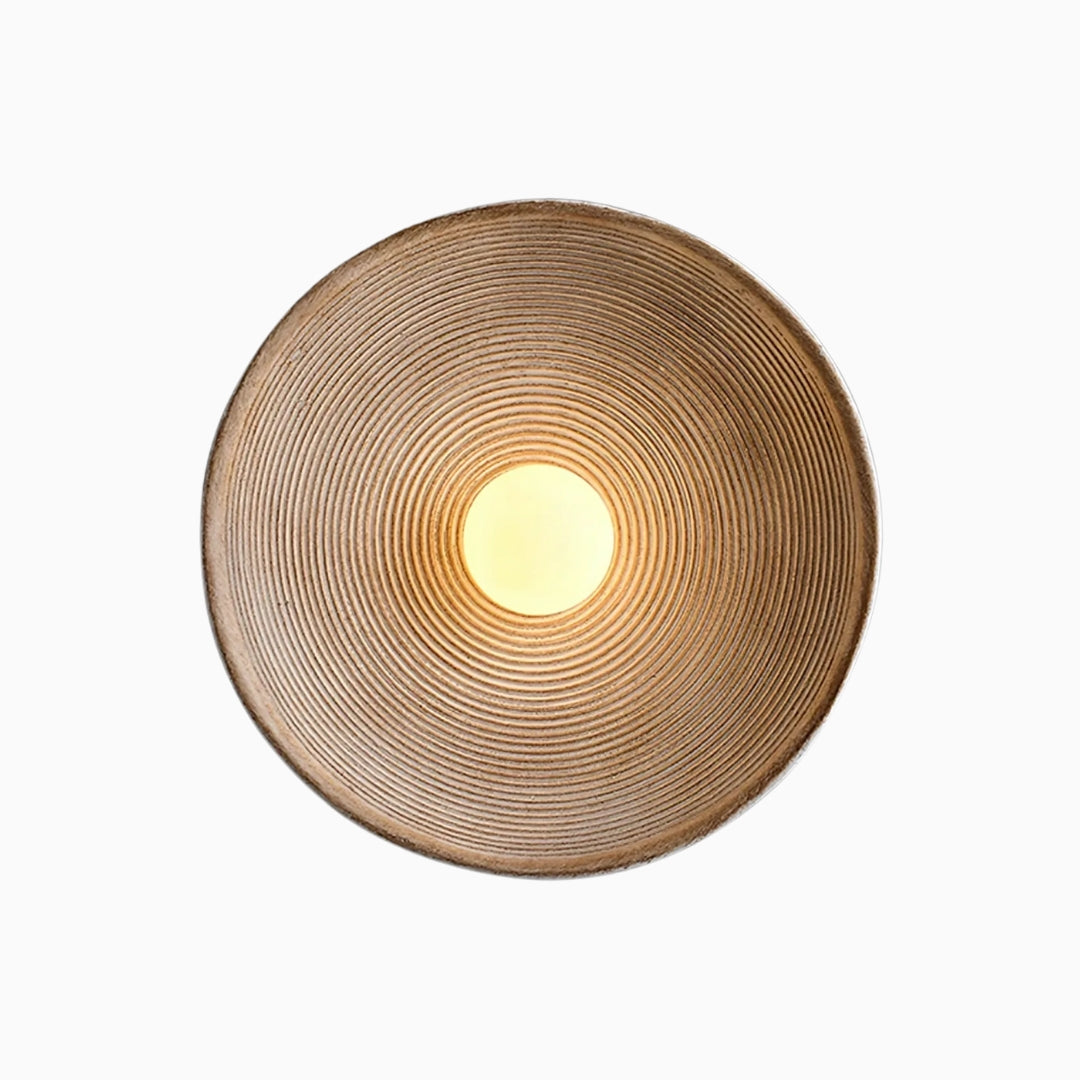 A modern resin wall lamp with a textured, concentric circular design, predominantly in brown color, intended to provide warm, ambient lighting.