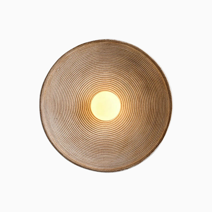A modern resin wall lamp with a textured, concentric circular design, predominantly in brown color, intended to provide warm, ambient lighting.